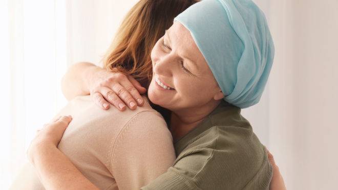 Woman hugging her mother with cancer indoors
