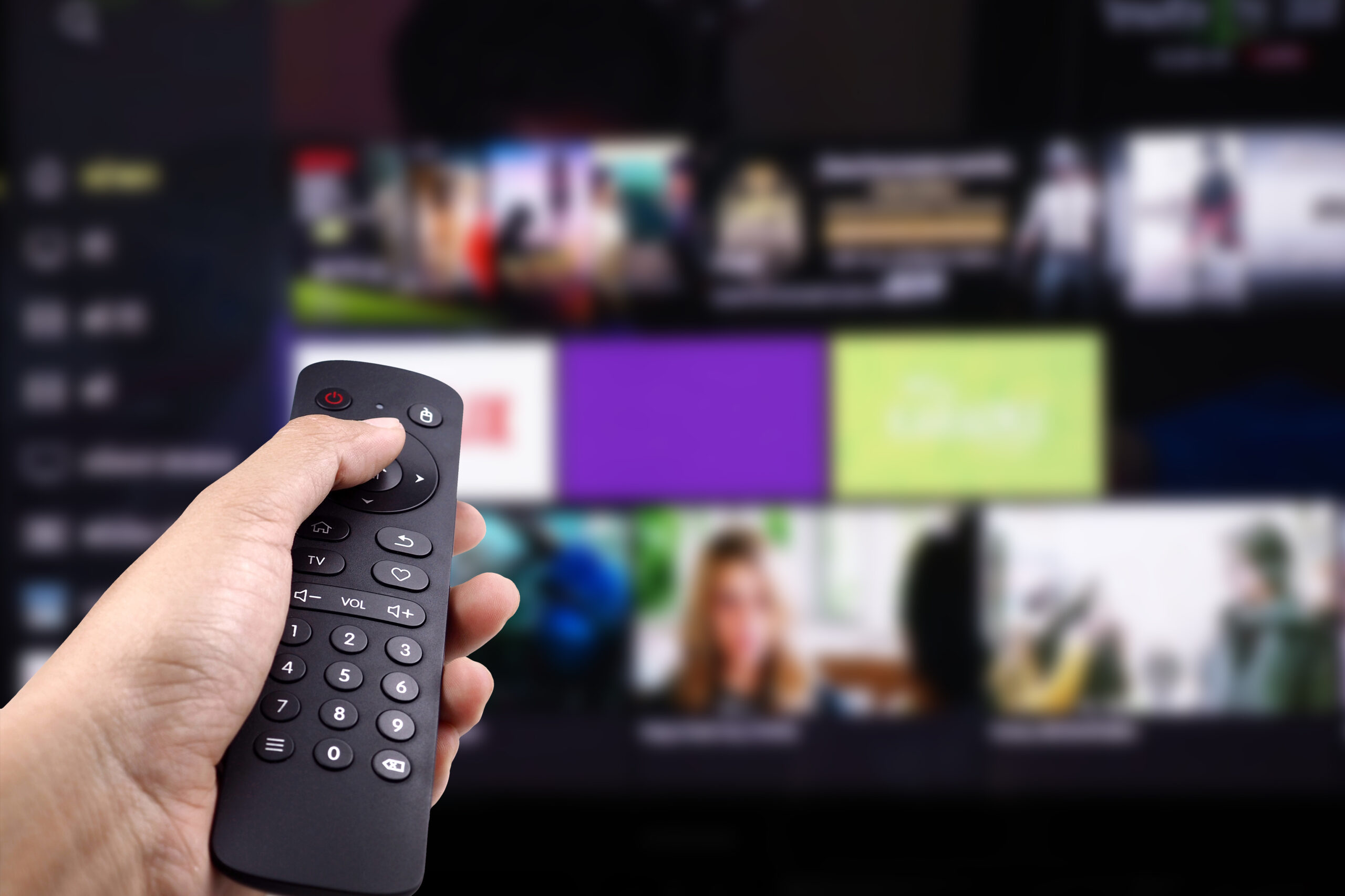 hand holding tv remote control with smart tv scaled