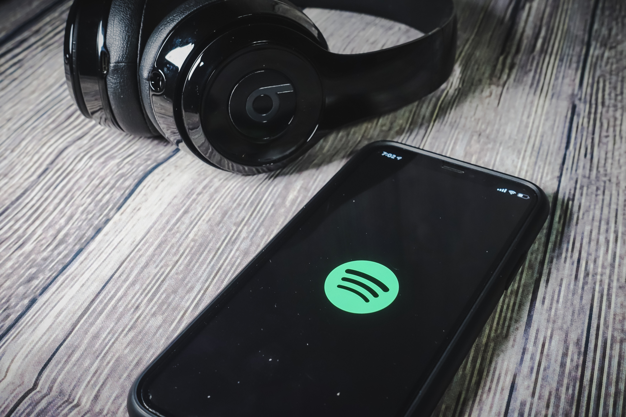 An iphone 11 screen showing spotify icon with beats earphone, perfect for listening musics on the go