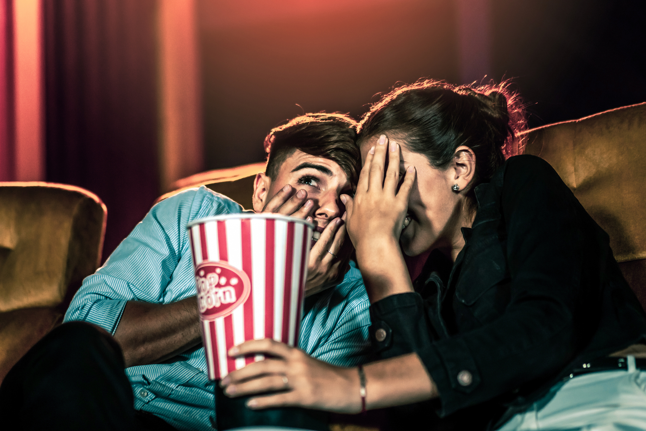 A couple of lovers watching movie shock and eyes close in the movie theater cinema.