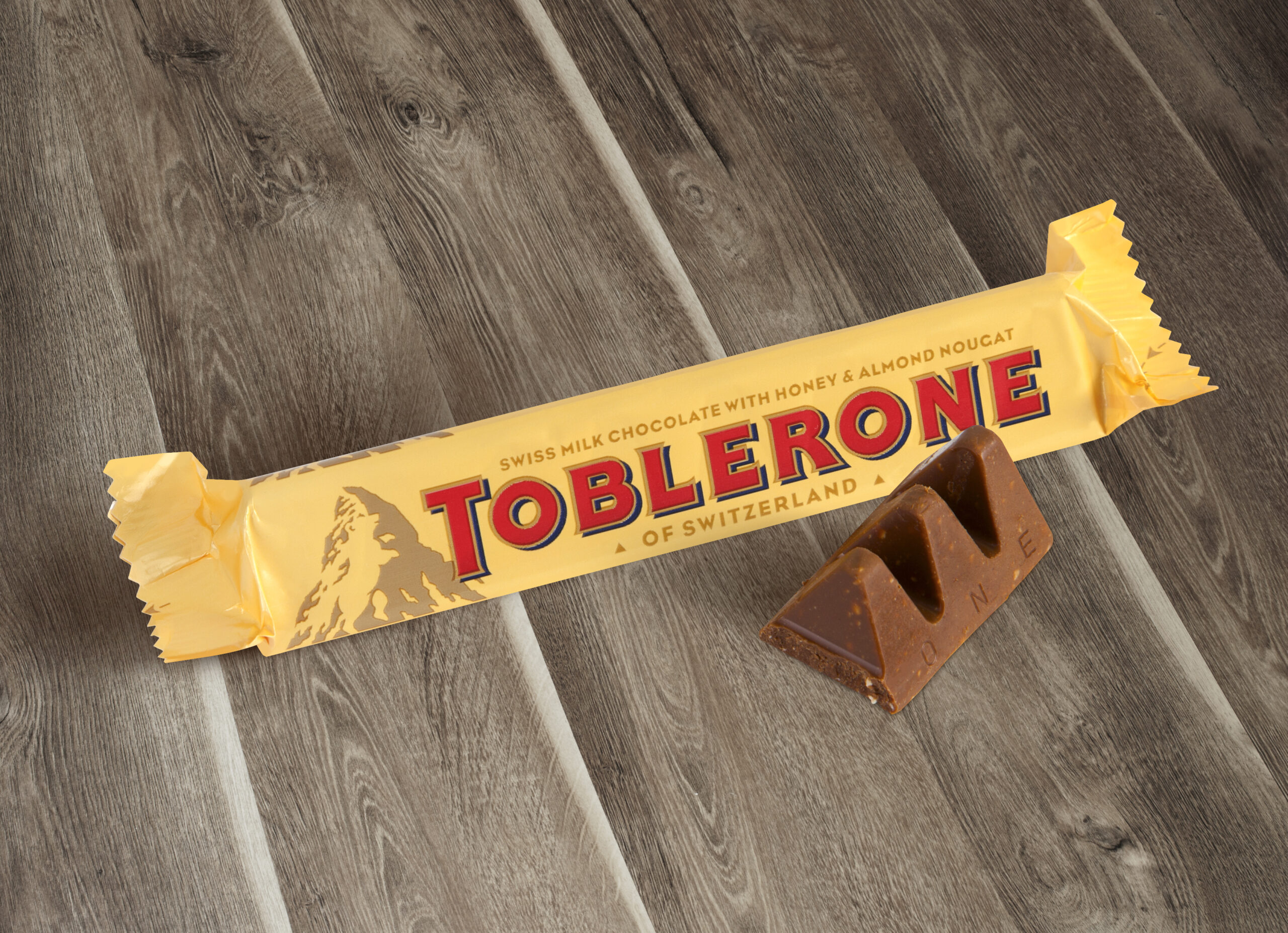 Chisinau, Moldova - June 14, 2016: A bar of Toblerone - Swiss milk chocolate with honey and almond nougat on a wood background. With clipping path.