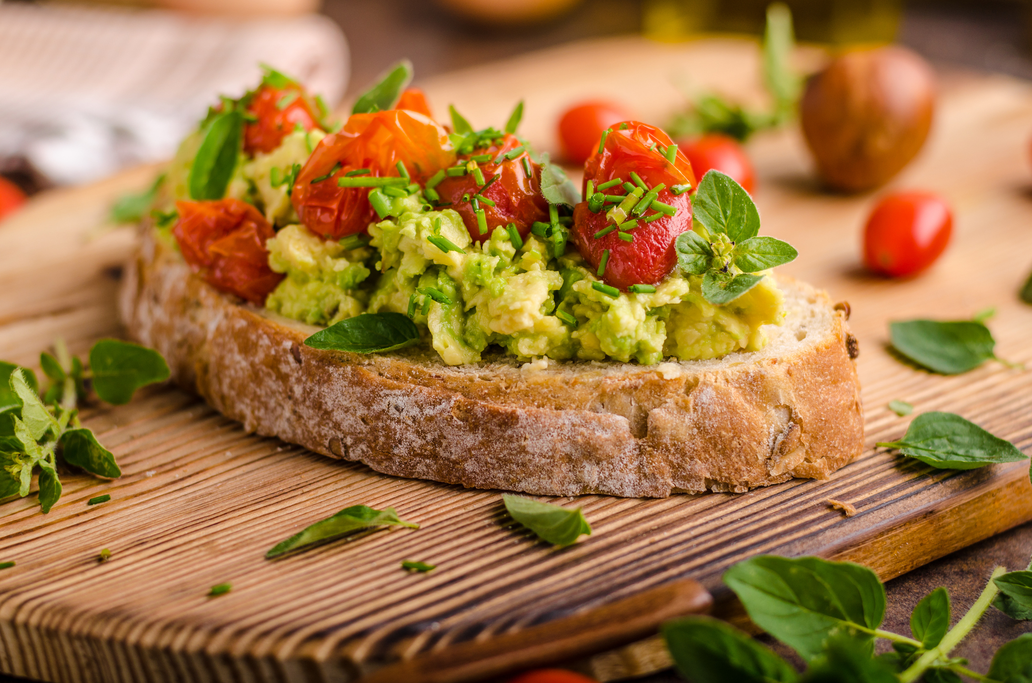 Avocado spread with tomatoes, roasted tomatoes and herbs on top