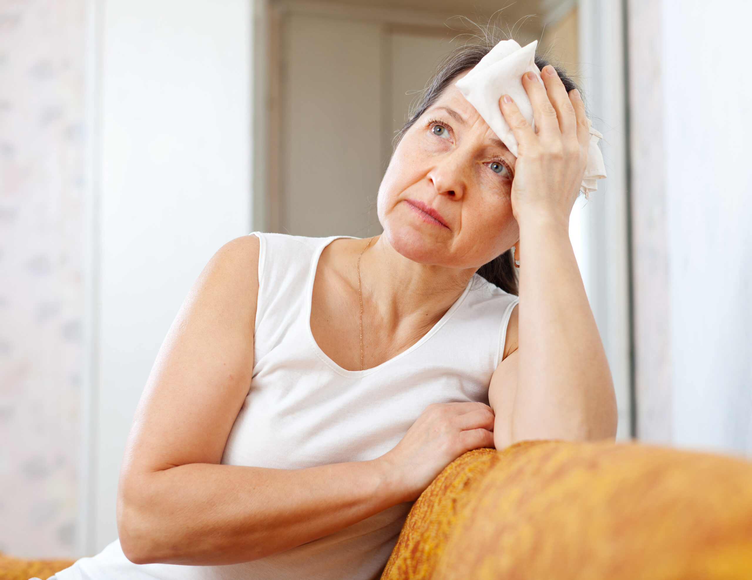 mature woman uses handkerchief on her head in home