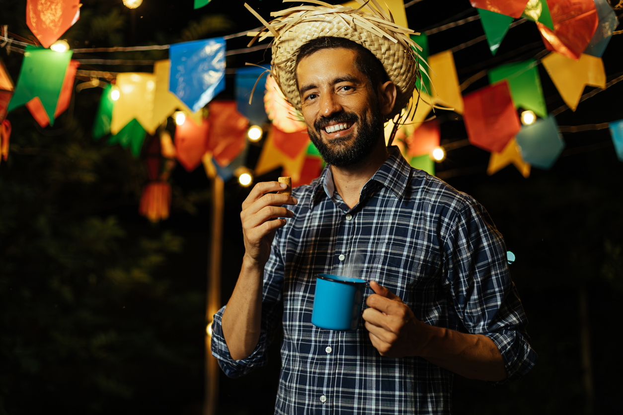 A man relishes Paçoca, a sweet peanut candy, and Quentão, a spiced hot beverage, at a vibrant June Festival in Brazil - Festa Junina