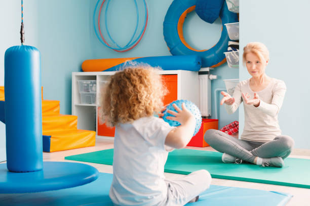 Boy playing with his therapist using a ball