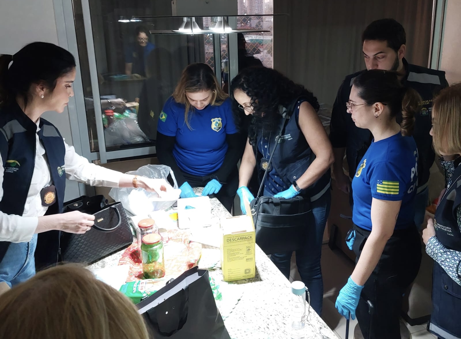 Agentes de segurança pública vasculham caixas em busca de provas em um dos endereços alvos de busca e apreensão | Foto: Divulgação/PCGO