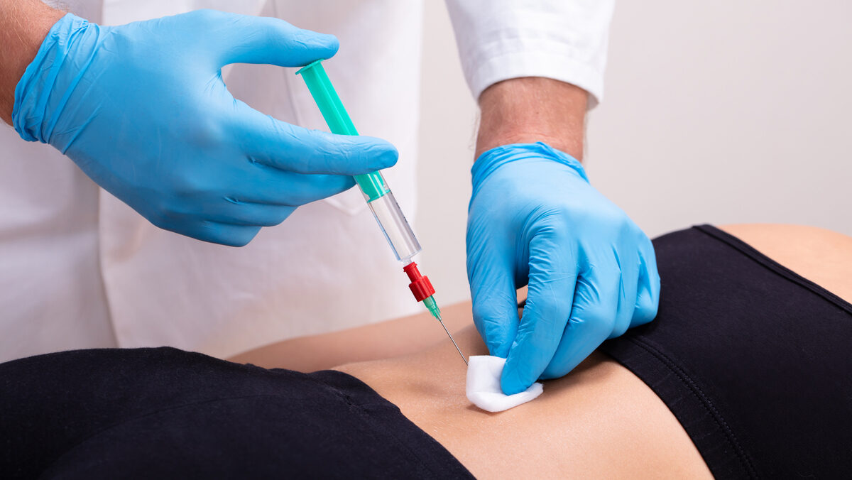 Doctor Giving Female Patient An Injection On Her Back In The Clinic