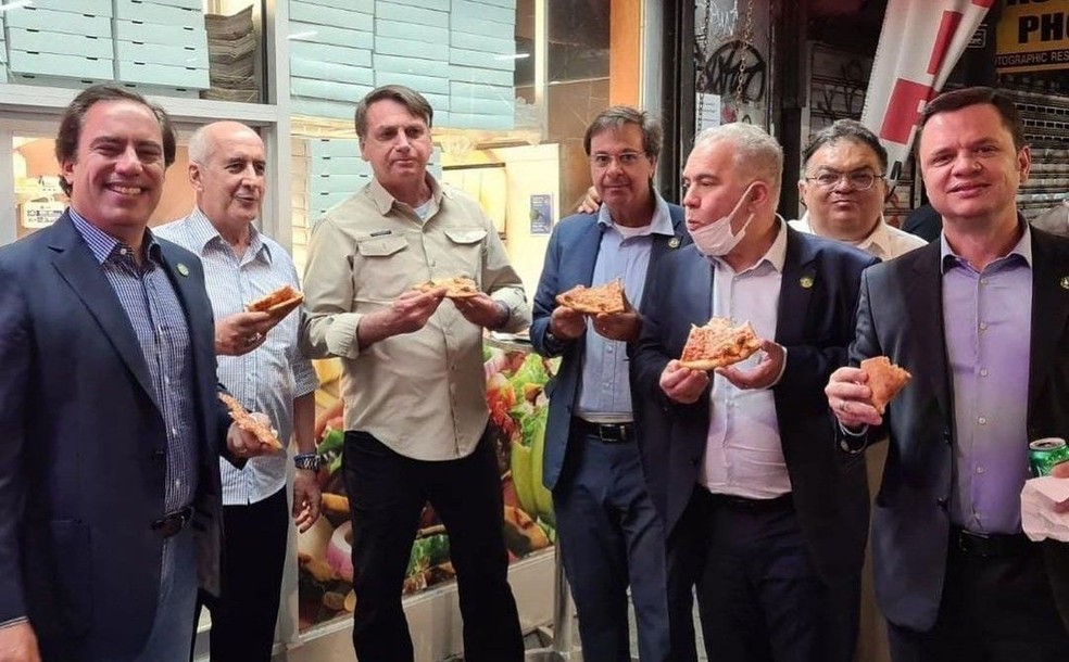Imagem Ilustrando a Notícia: Proibido de entrar em restaurante por não se vacinar, Bolsonaro come pizza na rua