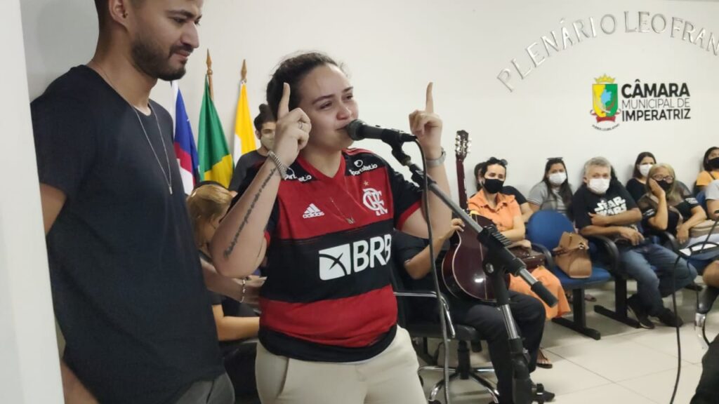 Imagem Ilustrando a Notícia: Vestida com camisa de time do Maurílio, Luíza discursa, chora e se despede