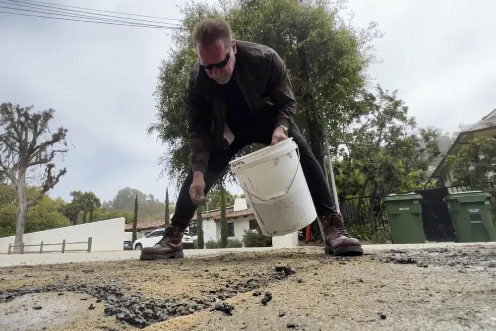 Imagem Ilustrando a Notícia: Arnold Schwarzenegger toma iniciativa e aparece tampando buraco de estrada no bairro onde mora