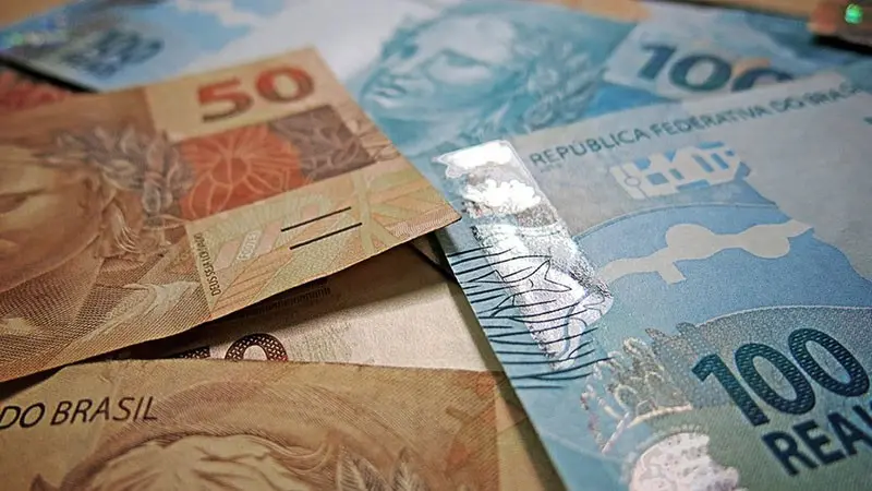 Mesmo com o prejuízo, o banco lucra mais com a conversão em reais