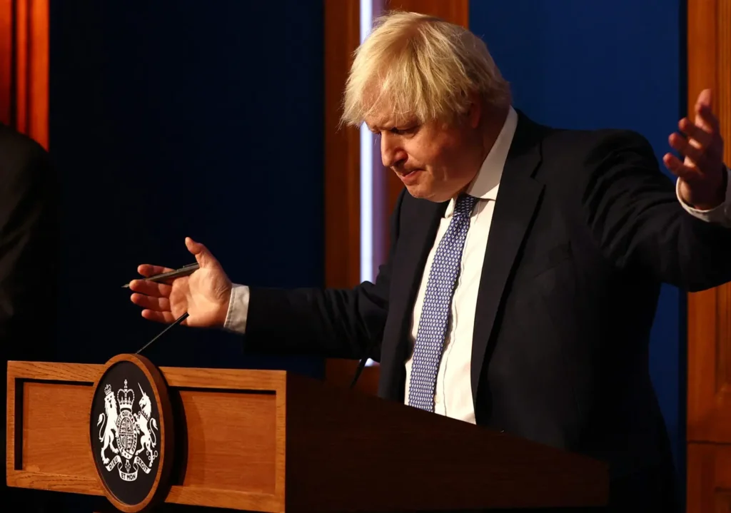 Britain's Prime Minister Boris Johnson gestures during a press conference for the latest Covid-19 update in the Downing Street briefing room in central London on December 8, 2021. - The UK government is reintroducing Covid-19 restrictions due to the Omicron variant. (Photo by Adrian DENNIS / POOL / AFP)