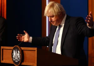 Britain's Prime Minister Boris Johnson gestures during a press conference for the latest Covid-19 update in the Downing Street briefing room in central London on December 8, 2021. - The UK government is reintroducing Covid-19 restrictions due to the Omicron variant. (Photo by Adrian DENNIS / POOL / AFP)