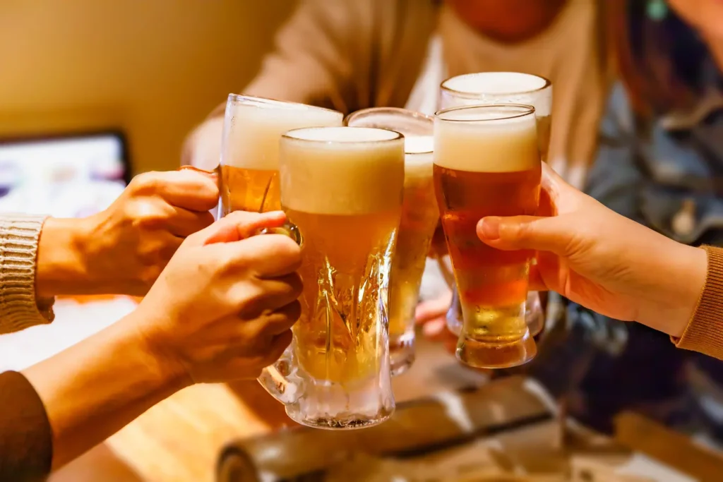 Hands and mug beer of many people toasting at a tavern