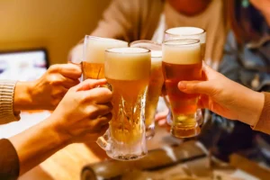 Hands and mug beer of many people toasting at a tavern