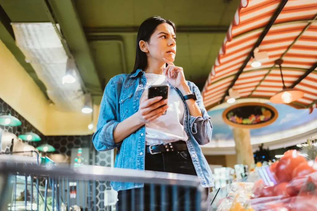 Brunette woman with mobile phone at grocery store