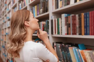 Rear view shot of a woman looking at the bookshelves thoughtfully, copy space
