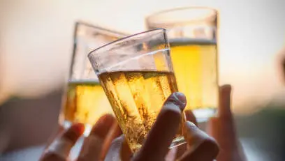 Hands toasting with glasses of beer in the late afternoon.