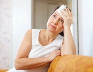 mature woman uses handkerchief on her head in home