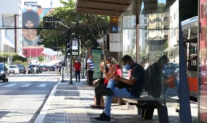 Usuários de transporte público usam máscaras de proteção contra covid-19 em ponto de ônibus na rua da Consolação
