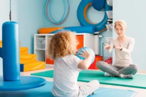 Boy playing with his therapist using a ball