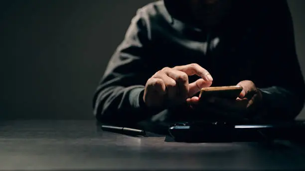 Hacker, thief is using their fingers to press passwords to break into personal data on smartphones. Concept of personal data hacking and financial hacking.