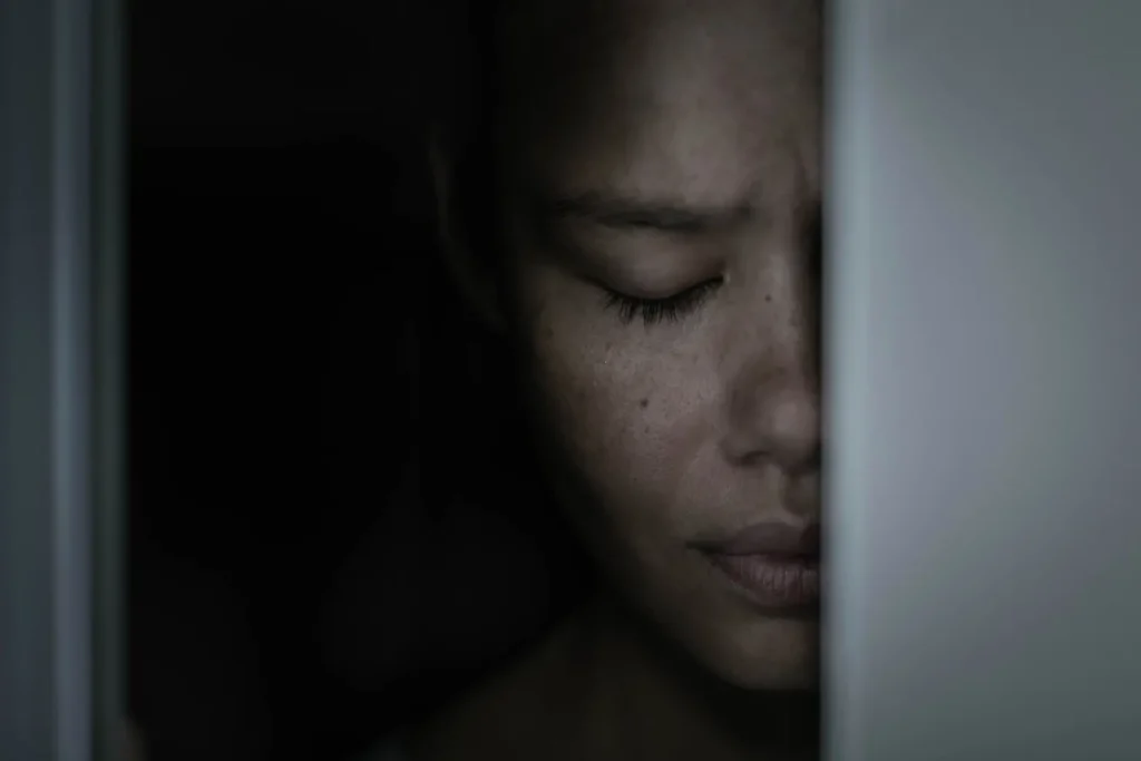 A scaared woman depressed hiding in the closet ashamed and frightened.