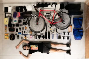 Pedro Paulo Medrado, 23, deitado no chão ao lado de sua bicicleta e demais itens que usa para a viagem | Foto: Divulgação