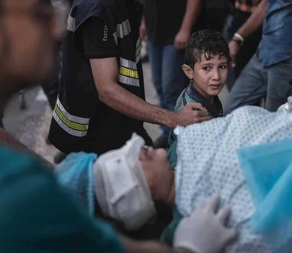Criança assustada vendo a mãe entrar no hospital depois de ter sido ferida por um ataque aéreo israelense | Foto: Motaz Azaiza