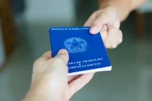 High resolution image. Hands of a worker holding a portfolio of Brazilian workers (Translation "Work Permit, Ministry of Labor and Social Security Brazil CTPS"). New job.