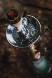 A vertical shot of a metal hookah with coals on it