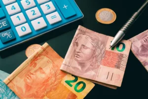 Real currency, money from Brazil. Some Brazilian Real banknotes on a dark table with a calculator, pen and some coins for Brazilian economy, finance and investment concept.