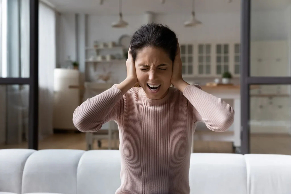 Too much noise. Anxious young hispanic woman shout stop cover ears with palms unable to hear loud music noisy sound. Angry frustrated millennial female get mad hate listening disturbing noise indoors