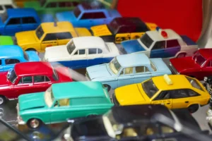 Big collection of retro car models on the shelf. Miniatures of colorful vintage vehicles in the shop. Selective focus.