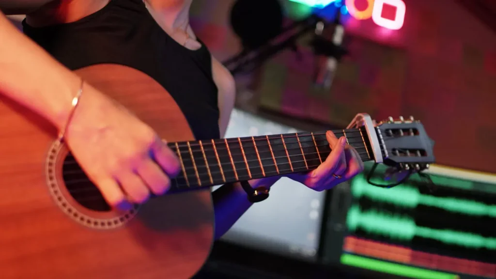 Woman playing guitar in an environment of audio recording computer and studio and gaming lights