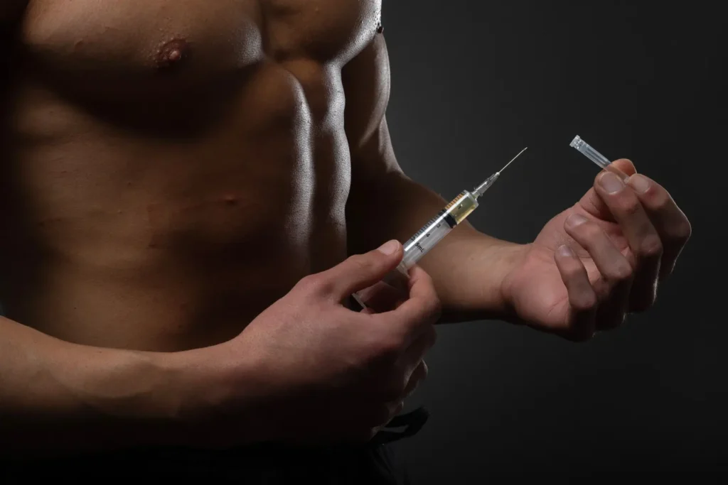 Muscular man with a syringe in his hand. User of anabolic steroids for strength training