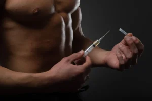 Muscular man with a syringe in his hand. User of anabolic steroids for strength training