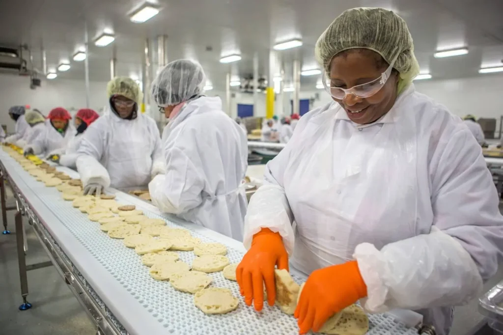 Trabalhadores em ação na linha de produção de uma fábrica de alimentos | Foto: Reprodução