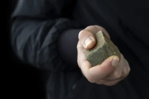 Cobblestone in male hand on black background. Riot concept.
