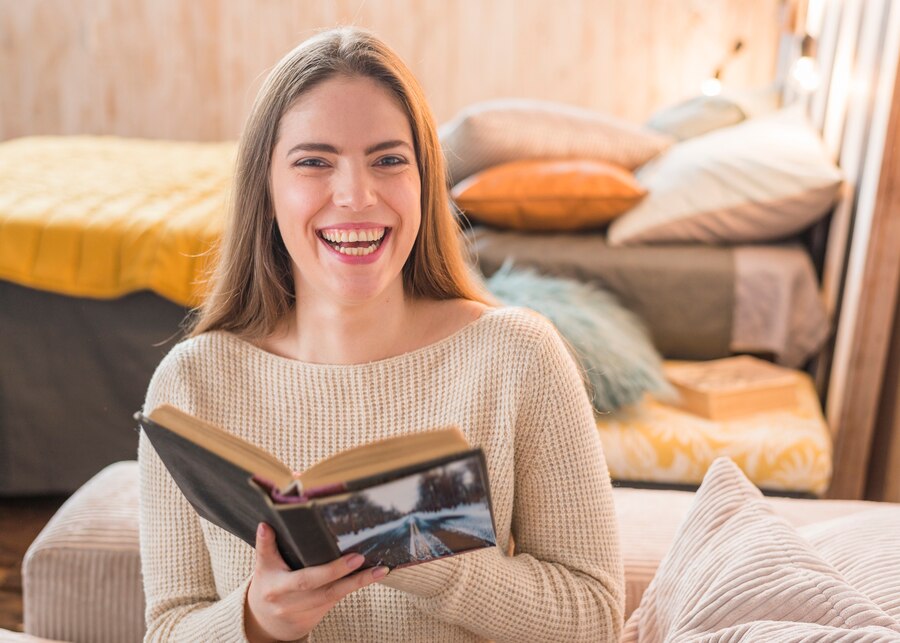 jovem alegre rindo enquanto lendo o livro em casa 23 2147975266