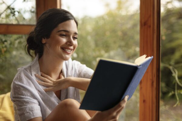 livro de leitura de mulher sorridente em plano medio scaled 1