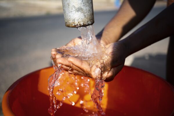 mulher africana servindo agua em um recipiente ao ar livre scaled 1