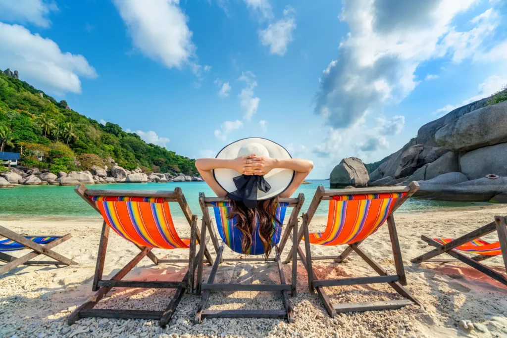 mulher com chapeu sentado na praia de cadeiras na bela praia tropical mulher relaxando em uma praia tropical na ilha de koh nangyuan