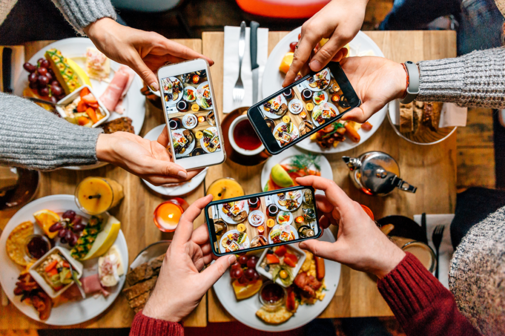 Amigos tirando fotos da comida na mesa com smartphones durante o brunch em um restaurante