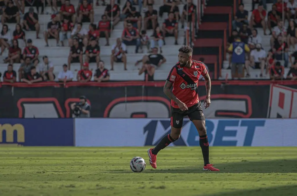 Meia Robert durante a vitória do Atlético Goianiense contra o Amazonas. Ele veste a camisa 10, está com a bola dominada e ao fundo temos algumas pessoas na torcida