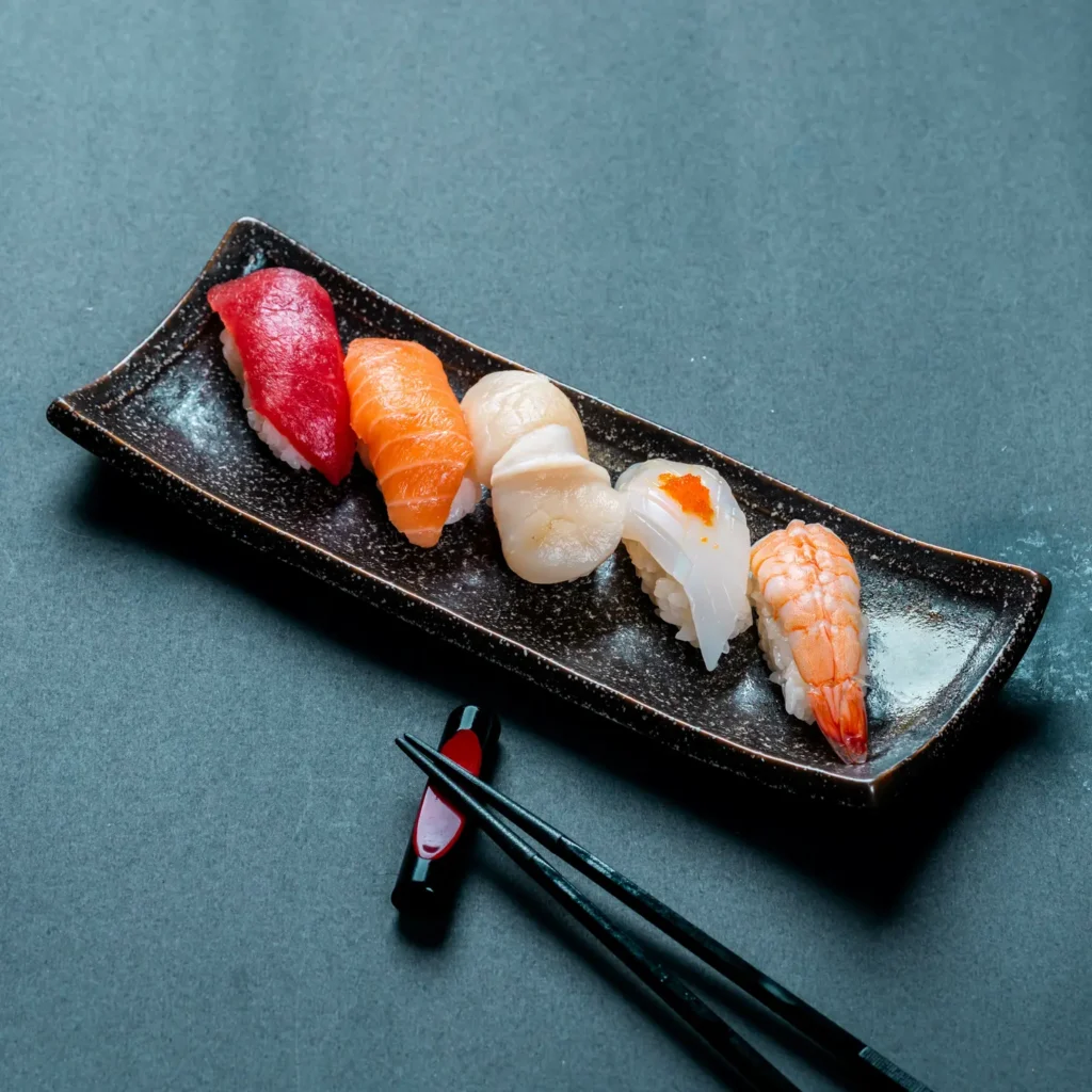 vertical shot fresh tuna salmon scallop nigiri shrimp sushi chopsticks