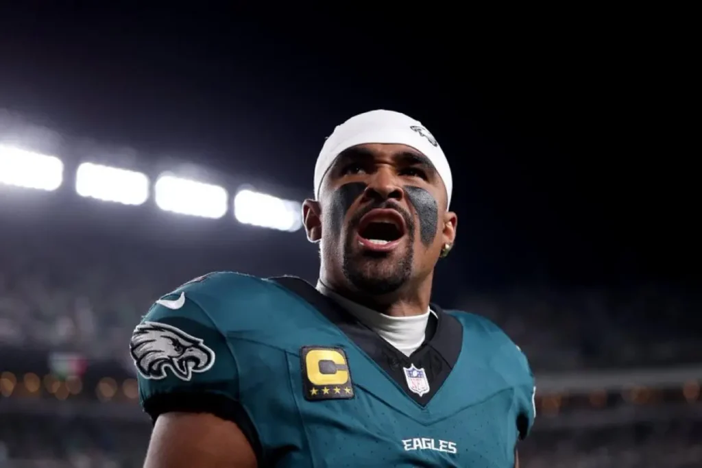 Jaylen Hurts comemorando um touchdown. Ele veste uniforme verde do Philadelphia Eagles e tem uma faixa na cabeça