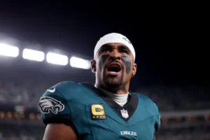 Jaylen Hurts comemorando um touchdown. Ele veste uniforme verde do Philadelphia Eagles e tem uma faixa na cabeça